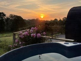 A hot tub on a deck with flowers and a sunset at Embden Pod at Banwy Glamping Llanfair Caereinion