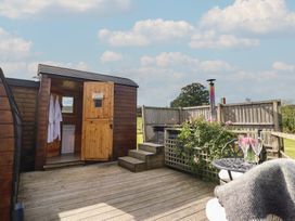 An outdoor area with a wooden cabin and seating at Embden Pod at Banwy Glamping Llanfair Caereinion