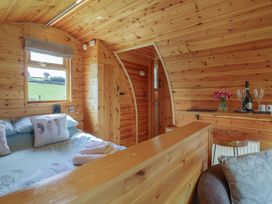 A bedroom with a bed, window, and small table at Embden Pod at Banwy Glamping Llanfair Caereinion