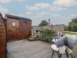 An outdoor space with a wooden shed, a table, and chairs at Embden Pod at Banwy Glamping, Llanfair Caereinion