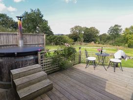 An outdoor area with a hot tub, table, and chairs at Embden Pod at Banwy Glamping, Llanfair Caereinion
