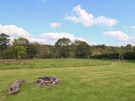 An outdoor area with a fire pit and surrounding trees at Embden Pod at Banwy Glamping, Llanfair Caereinion