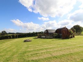 A garden with a building and trees at Embden Pod at Banwy Glamping in Llanfair Caereinion