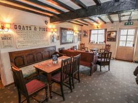 A seating area with wooden benches and chairs around tables in a room with carpet and windows at Heather in Graigfechan