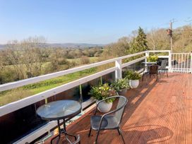 A balcony with black chairs tables and potted plants overlooking a rural landscape at Heather in Graigfechan