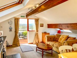 A living area with a sofa coffee table and kitchen appliances near a balcony door at Heather in Graigfechan