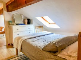 A bedroom with a bed pillow and blanket a white dresser with towels mirror and decor under a sloped ceiling with a skylight at Heather in Graigfechan