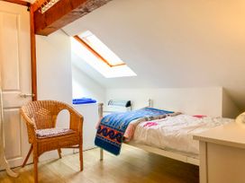 A bedroom with a bed a wicker chair and a skylight window at Heather in Graigfechan