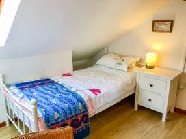 A bedroom with a single bed a bedside table with a lamp and a framed picture on the wall at Heather in Graigfechan