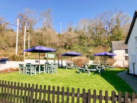 An outdoor garden area with picnic tables and umbrellas beside a white building at Heather in Graigfechan