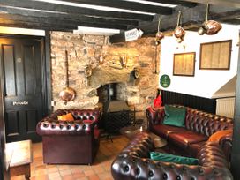 A sitting area with brown leather sofas and a stone fireplace with a black door marked private at Heather in Graigfechan