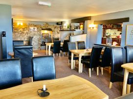 A dining area with wooden tables and black leather chairs inside a restaurant at Heather in Graigfechan