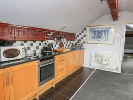 A kitchen with wooden cabinets a microwave oven a toaster and a kettle a framed picture hanging on the wall at Hillfort in Graigfechan