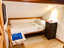 A small bedroom with a single bed a wooden chair with towels and a side table with a lamp at Hillfort in Graigfechan
