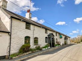 A white stone building with black framed windows and an entrance with a black porch on a street at Hillfort in Graigfechan