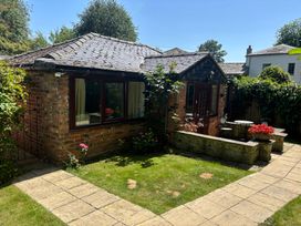 A garden with a brick building and seating area at Claire Cottage in Gateforth near Hambleton, North Yorkshire