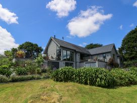 A grey house with a balcony and garden at Wood Meadow Helford