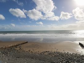 A beach with waves and a wooden pier at Stable Cottage, Narberth