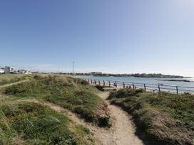 A pathway leading to an ocean with houses in the background at Haul a Gwynt Trearddur Bay