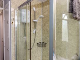 A shower with a towel and soap dispenser at Turtle Chalet in Dawlish Warren