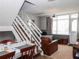 A living room with a dining table and staircase at Dolphin Chalet in Dawlish Warren