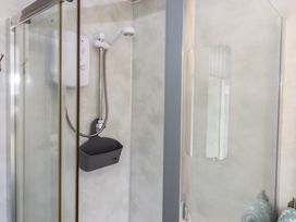 A shower with a wall and water heater at Dolphin Chalet Dawlish Warren