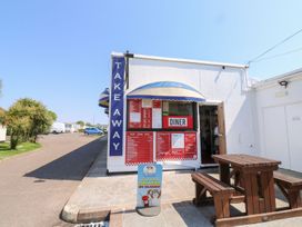 A takeaway with a menu board and wooden seating at Dolphin Chalet in Dawlish Warren