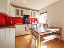 A kitchen with cabinets and a dining table at Redwood in Harlech