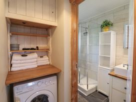 A bathroom featuring a washer, towels, shower, and sink at Redwood in Harlech