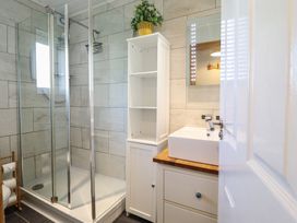 A bathroom with a shower and washbasin at Redwood Harlech