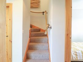 A staircase with a wooden handrail and door at Redwood in Harlech