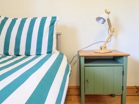 A bedroom with a striped bed and lamp on the nightstand at Redwood in Harlech