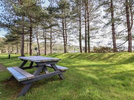 A picnic table in a grassy area surrounded by trees at Redwood in Harlech