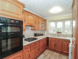 A kitchen with cabinets, oven, stove, sink and window at Breaking Waves in Burnham-On-Sea