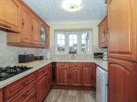 A kitchen with wooden cabinets and appliances at Breaking Waves in Burnham-On-Sea