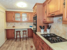 A kitchen with wooden cabinets and a gas stove at Breaking Waves in Burnham-On-Sea