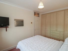 A bedroom with a bed, tv, and wardrobe at Breaking Waves in Burnham-On-Sea