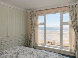 A bedroom with a window overlooking the beach at Breaking Waves in Burnham-On-Sea
