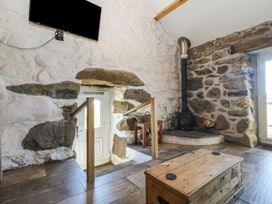 A living room with a wood stove and steps to a door at Ty Coch in Llanaelhaearn near Trefor, Caernarfon