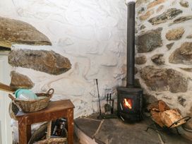 A living room with a wood stove and stone wall at Ty Coch near Llanaelhaearn Trefor, Caernarfon
