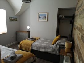 A bedroom with two single beds each with yellow blankets and gray towels on top at Y Bwthyn in Llanbedr