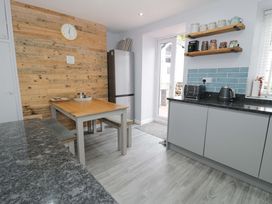 A kitchen with a dining table and benches at Y Bwthyn in Llanbedr