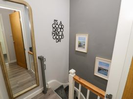 A hallway with a staircase and wall art at Y Bwthyn in Llanbedr