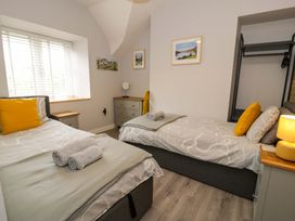 A bedroom with two single beds and a dresser at Y Bwthyn in Llanbedr