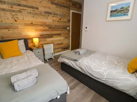 A bedroom with two beds and a bedside table at Y Bwthyn in Llanbedr