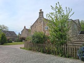 A garden with a stone house and a fence at Crooked Well in Timsbury, Nr Bath