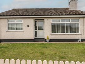 A front view of a house with a yard and fence at Hazel Cottage Portrush