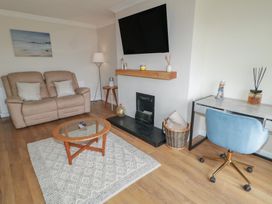 A living room with a sofa, coffee table, and desk at Hazel Cottage in Portrush