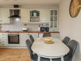 A kitchen with cabinets and a dining table at Hazel Cottage in Portrush