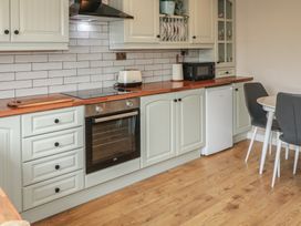 A kitchen with cabinets, oven, microwave and dining table at Hazel Cottage in Portrush